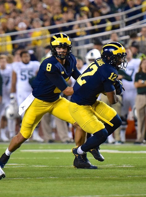 John O'Korn hands the ball off to Chris Evans during a night game against Michigan State.