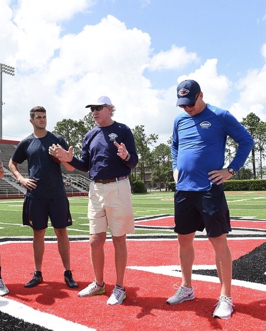 John O'Korn listens to instructions from Archie and Peyton Manning at the Manning Passing Academy.