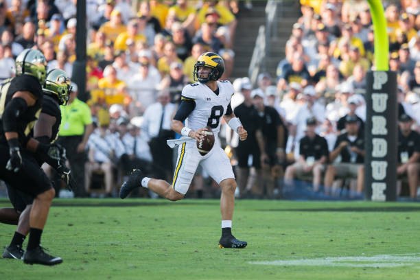 John O'Korn runs from two defenders against Purdue.