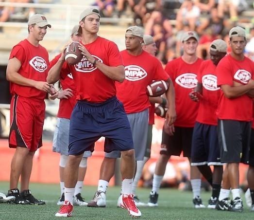 John O'Korn throws a pass at the 2014 Manning Passing Academy as Eli Manning, Dak Prescott, Marcus Mariota, and others look on.