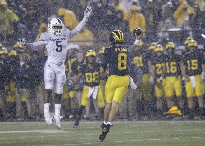 John O'Korn throws a pass in the rain at Michigan Stadium against the Michigan State Spartans.