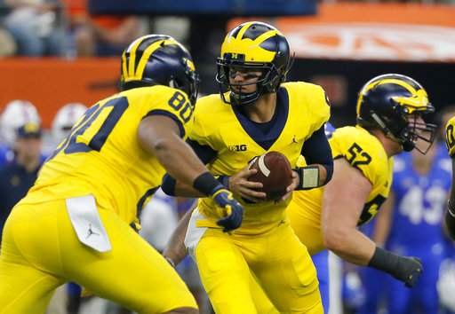 John O'Korn turns to hand the ball off as Michigan beats Florida at AT&T Stadium in week one of the 2017 season.